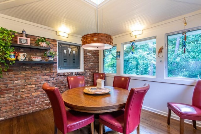 dining space with brick wall and dark hardwood / wood-style flooring