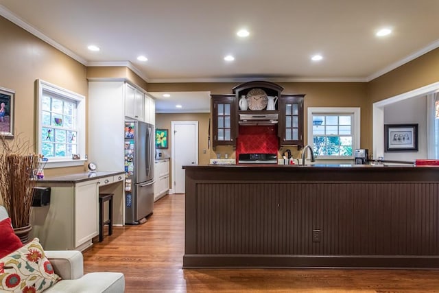 kitchen with extractor fan, white cabinetry, stainless steel fridge, a healthy amount of sunlight, and wood-type flooring