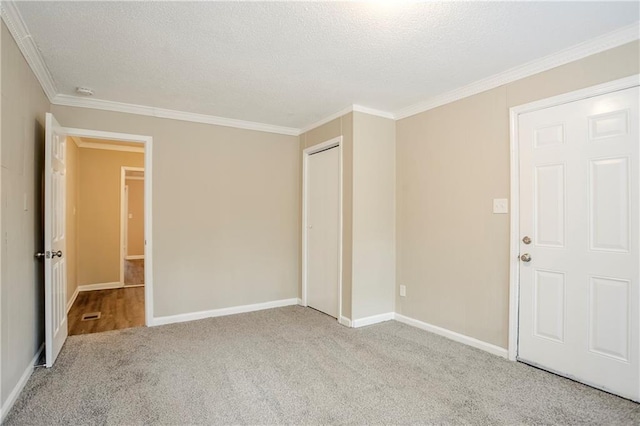 unfurnished room with crown molding, light colored carpet, and a textured ceiling