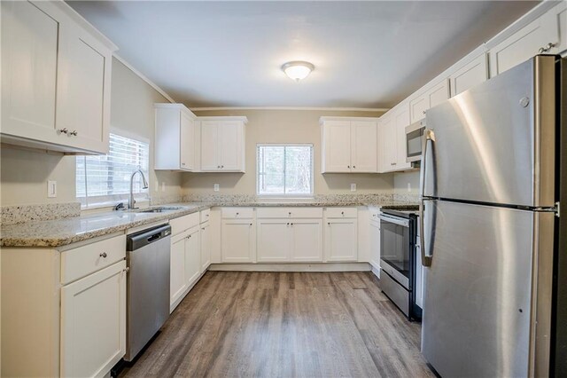 kitchen with stainless steel appliances, light stone countertops, sink, and white cabinets