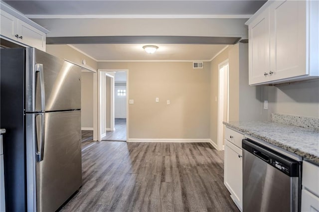 kitchen with appliances with stainless steel finishes, hardwood / wood-style floors, ornamental molding, light stone countertops, and white cabinets