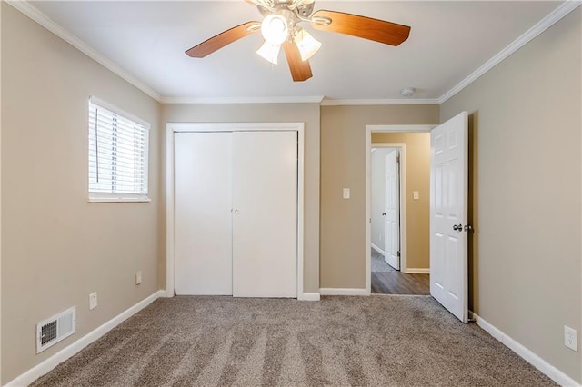 unfurnished bedroom with ceiling fan, ornamental molding, a closet, and carpet