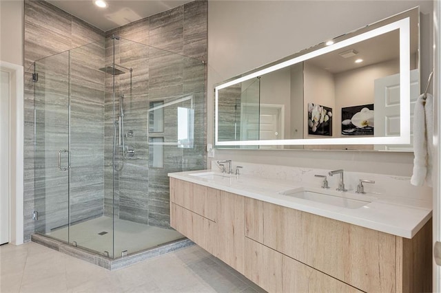 bathroom featuring a shower stall, double vanity, and a sink