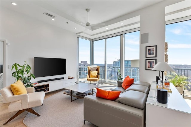 living area with a wall of windows, recessed lighting, wood finished floors, and visible vents