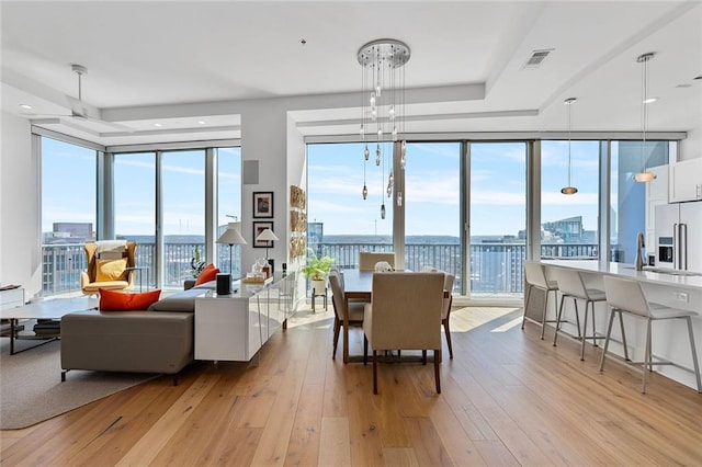 dining area featuring visible vents, a city view, a wall of windows, and light wood-style floors