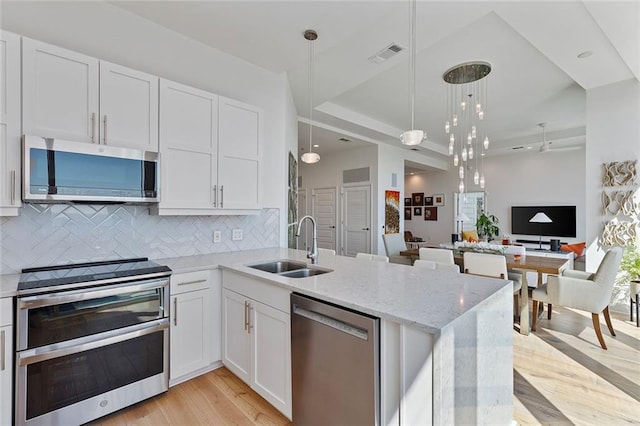 kitchen with a sink, tasteful backsplash, white cabinetry, stainless steel appliances, and light stone countertops