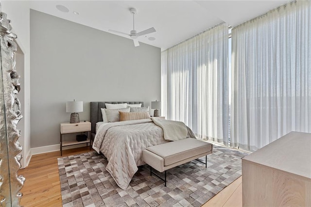 bedroom with light wood-type flooring, baseboards, a ceiling fan, and vaulted ceiling