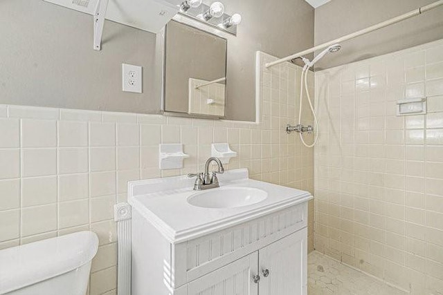 bathroom featuring tile walls, vanity, toilet, and a tile shower