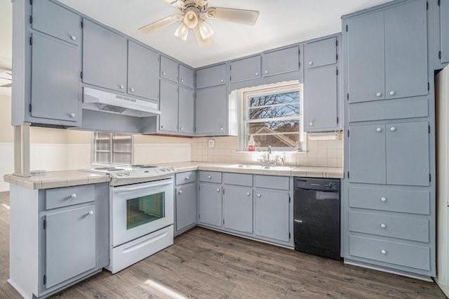 kitchen with sink, white electric range, dishwasher, dark hardwood / wood-style floors, and tile countertops