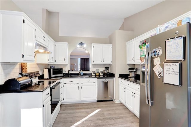 kitchen with white cabinets, dark countertops, tasteful backsplash, appliances with stainless steel finishes, and under cabinet range hood
