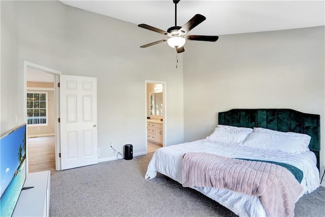 bedroom with carpet, baseboards, a towering ceiling, ceiling fan, and ensuite bathroom