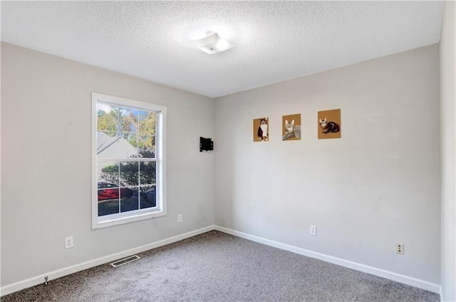 empty room with baseboards, carpet floors, a textured ceiling, and visible vents