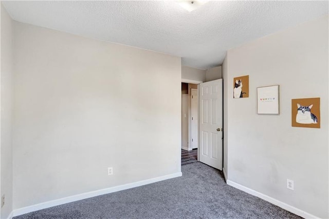 unfurnished room featuring carpet, baseboards, and a textured ceiling