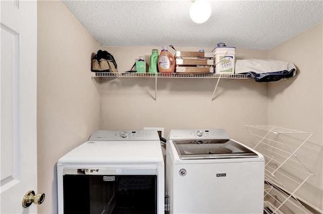 washroom featuring washing machine and clothes dryer, laundry area, and a textured ceiling