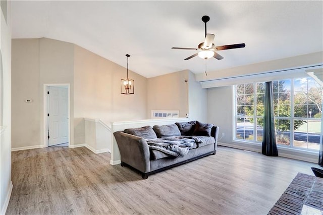 living area with ceiling fan with notable chandelier, lofted ceiling, wood finished floors, and baseboards