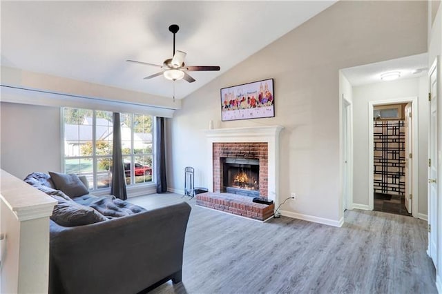 living area featuring lofted ceiling, baseboards, a ceiling fan, a fireplace, and wood finished floors