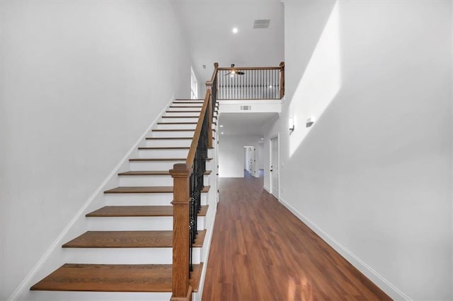 stairway with hardwood / wood-style flooring and a high ceiling