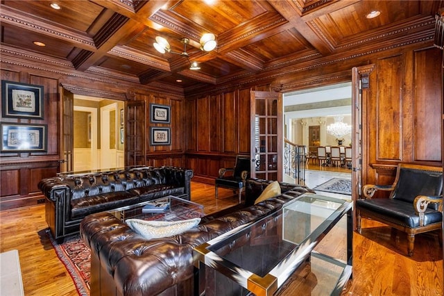 living room with wood walls, ornamental molding, coffered ceiling, wood ceiling, and light wood-type flooring