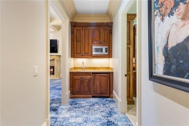 bar featuring stainless steel microwave, sink, and crown molding