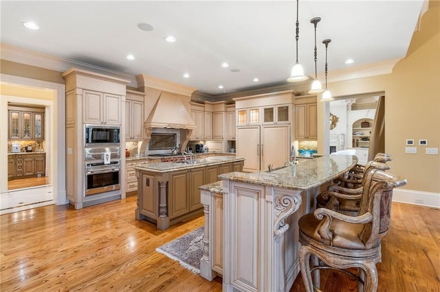 kitchen with premium range hood, a breakfast bar, stainless steel oven, a center island with sink, and black microwave