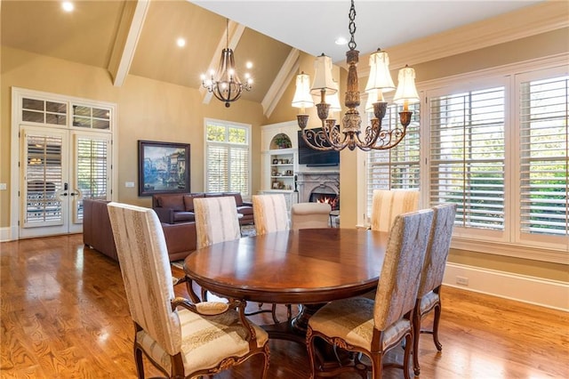 dining room featuring vaulted ceiling with beams, a chandelier, and light hardwood / wood-style flooring