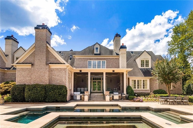 back of property with a swimming pool with hot tub, a sunroom, and a patio area