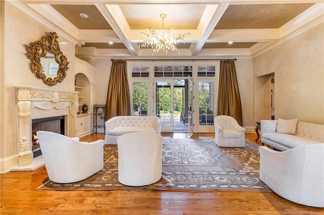 interior space featuring beamed ceiling, hardwood / wood-style flooring, coffered ceiling, a high end fireplace, and an inviting chandelier