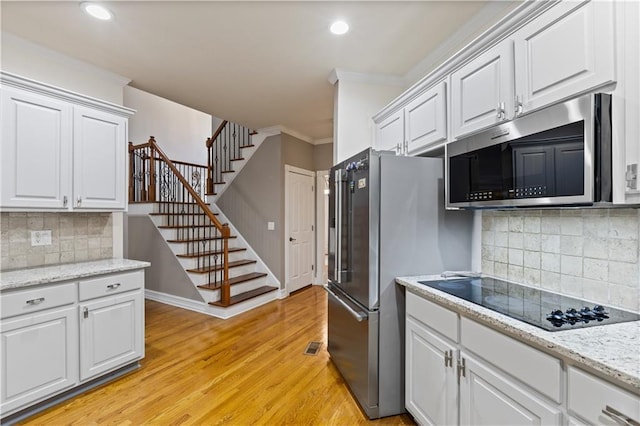 1360 Mount Mickinley Dr, Grayson, GA 30017 - kitchen with appliances with stainless steel finishes, crown molding, white cabinetry, light wood-style floors, and decorative backsplash
