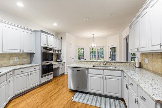 1360 Mount Mickinley Dr, Grayson, GA 30017 - kitchen featuring appliances with stainless steel finishes, a peninsula, light wood-style floors, tasteful backsplash, and recessed lighting
