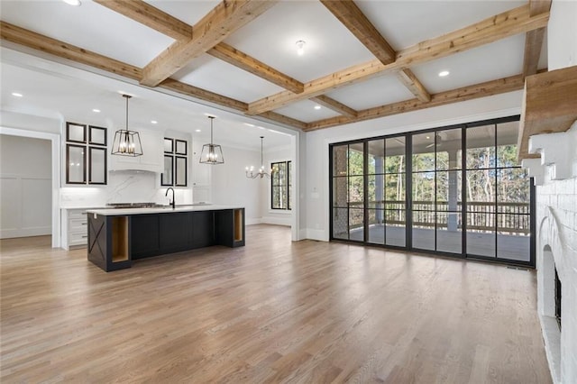 kitchen featuring light wood-style flooring, beam ceiling, light countertops, and a notable chandelier