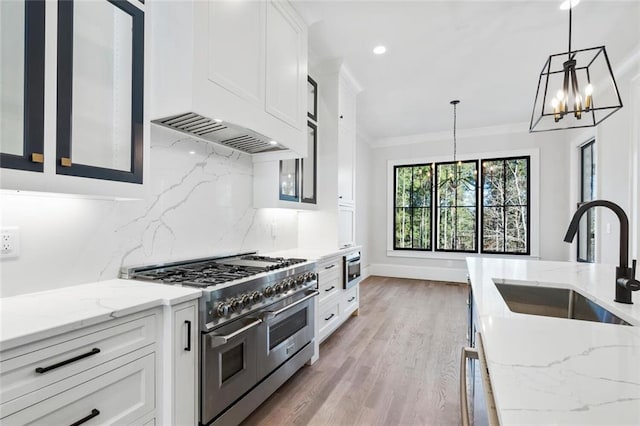 kitchen featuring range with two ovens, ornamental molding, hanging light fixtures, a sink, and backsplash