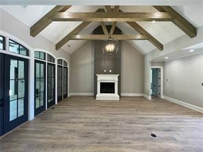 unfurnished living room with a fireplace, beamed ceiling, and wood finished floors