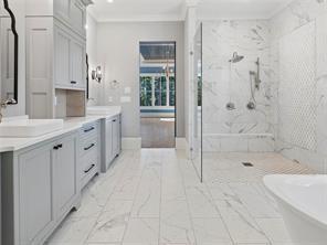 bathroom featuring ornamental molding, a freestanding bath, vanity, and a marble finish shower