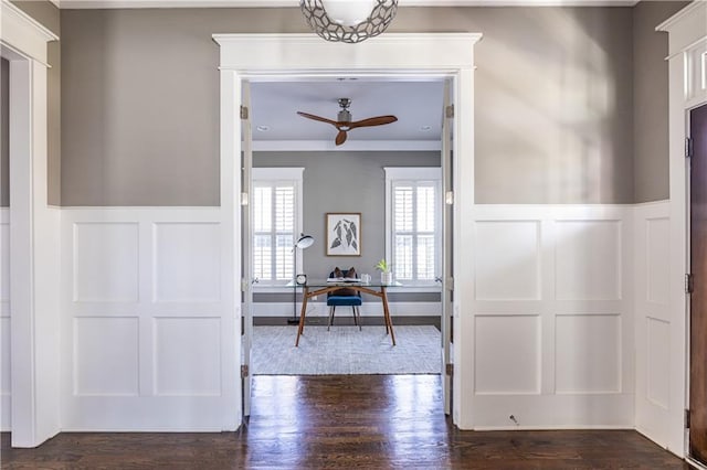 hall with dark wood finished floors, a decorative wall, wainscoting, and crown molding