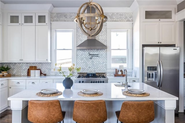 kitchen featuring a healthy amount of sunlight, an island with sink, a sink, stainless steel refrigerator with ice dispenser, and range