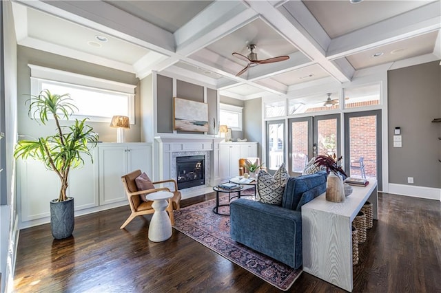 living area featuring wood finished floors, a healthy amount of sunlight, coffered ceiling, and a fireplace with raised hearth