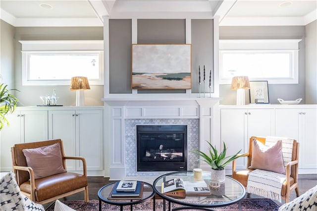 sitting room with a healthy amount of sunlight, wood finished floors, crown molding, and a tile fireplace