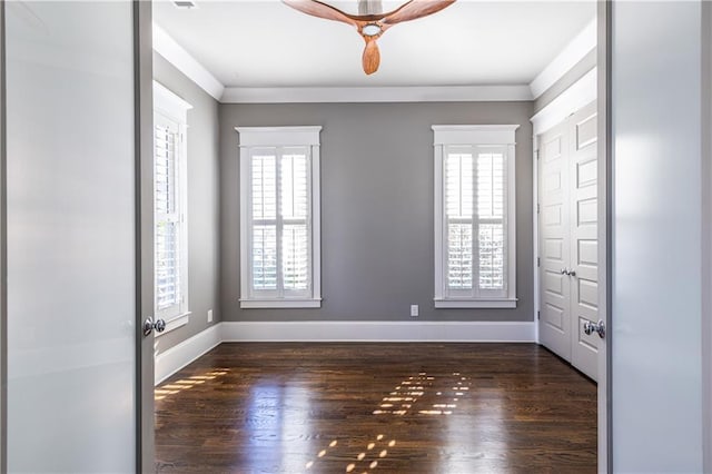 empty room with baseboards, dark wood finished floors, and ornamental molding