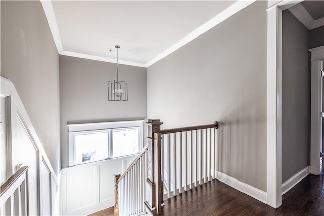 stairway featuring baseboards, an inviting chandelier, wood finished floors, and crown molding