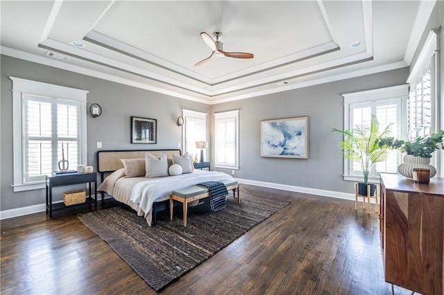 bedroom featuring dark wood-style floors, baseboards, crown molding, and a tray ceiling