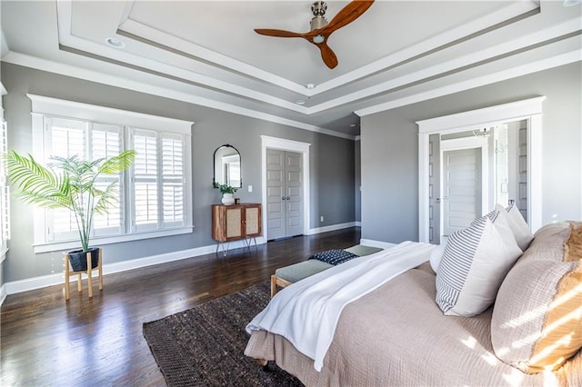 bedroom with a raised ceiling, crown molding, wood finished floors, and baseboards