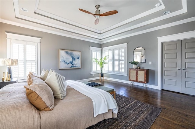 bedroom with crown molding, a raised ceiling, baseboards, and wood finished floors