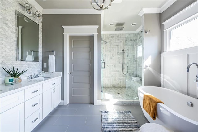 bathroom with a stall shower, backsplash, tile patterned flooring, a freestanding bath, and vanity