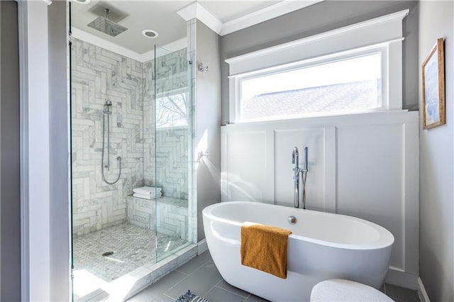 full bathroom with a soaking tub, a stall shower, crown molding, a decorative wall, and tile patterned floors