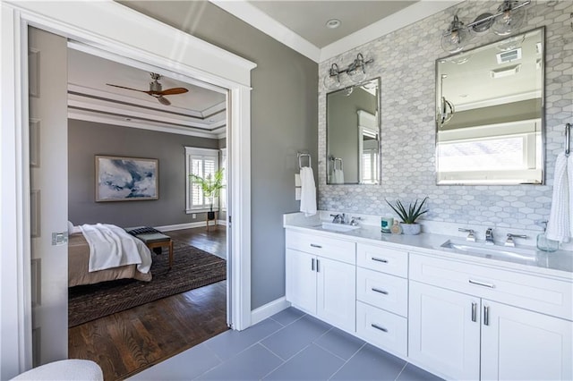 ensuite bathroom with ceiling fan, ornamental molding, tasteful backsplash, and a sink