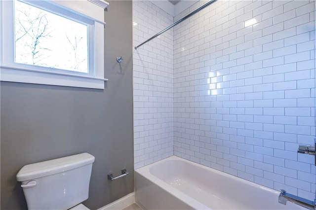 bathroom with baseboards, toilet, and shower / bathtub combination