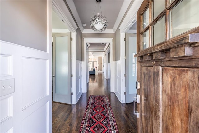 hallway with a decorative wall, dark wood-style floors, and a wainscoted wall