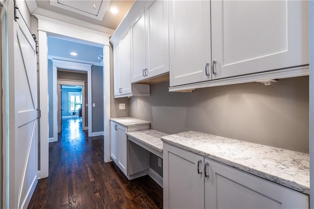 kitchen featuring dark wood-style floors, baseboards, light stone countertops, white cabinets, and a barn door