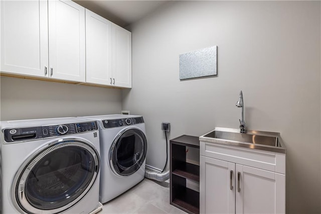 washroom with light tile patterned flooring, cabinet space, washer and dryer, and a sink