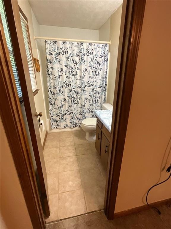 full bathroom featuring shower / bath combo with shower curtain, toilet, vanity, and tile patterned flooring